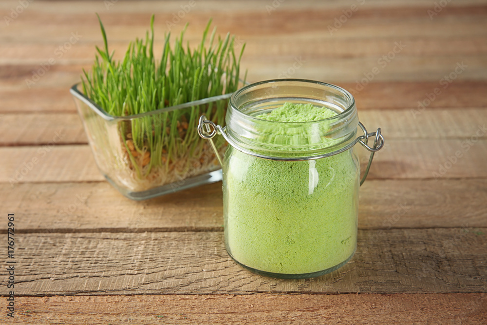 Jar with natural wheat grass powder and sprouts in bowl on wooden background Jar with natural wheat grass powder and sprouts in bowl on wooden background