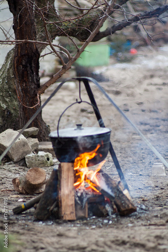metal pot with a meal basking blured on burning firewood in the forest wildlife