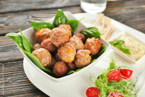 Sausage cheese balls served with sauce and vegetables on white plate