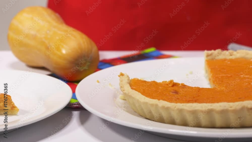 Making homemade pumpkin pie for Thanksgiving dinner. Pumpkin pie slice decorated with powdered sugar on a plate. Woman tasting her freshly baked pie. Panning right to left. Making homemade pumpkin pie for Thanksgiving dinner. Pumpkin pie slice decorated with powdered sugar on a plate. Woman tasting her freshly baked pie. Panning right to left.