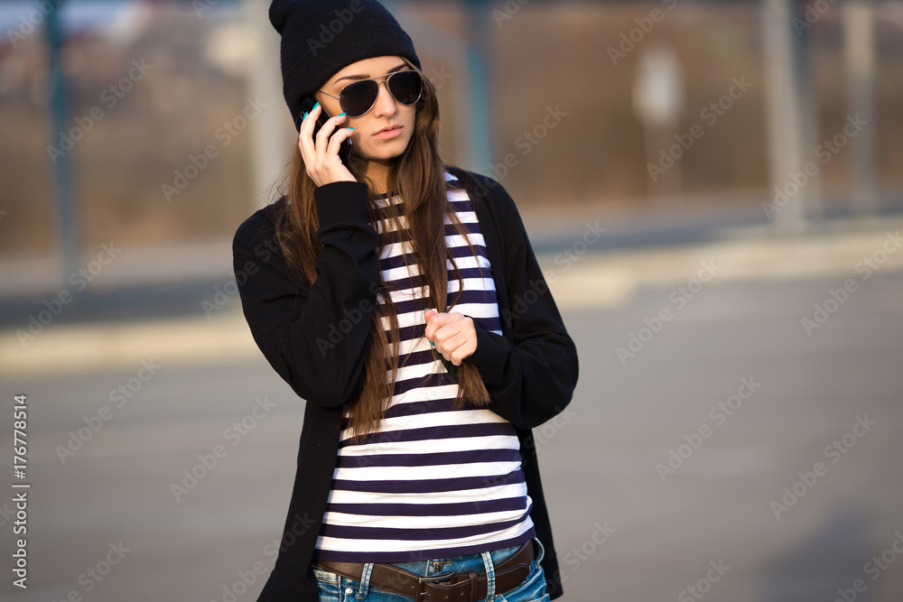 Outdoor fashion closeup portrait of nice pretty young hipster woman posing in sunglasses at sunset walks along the streets of the city.