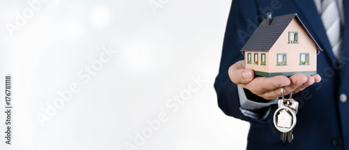 Real estate agent with home keys and house miniature photo