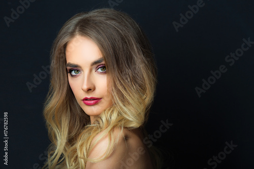 portrait of a beautiful young girl with makeup and hairdress on a black background