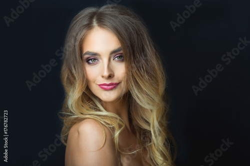 portrait of a smiling beautiful young girl with makeup and hairdress on head on a black background