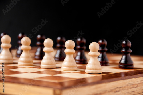 Still life on the chessboard  white and black pawns stand in a row