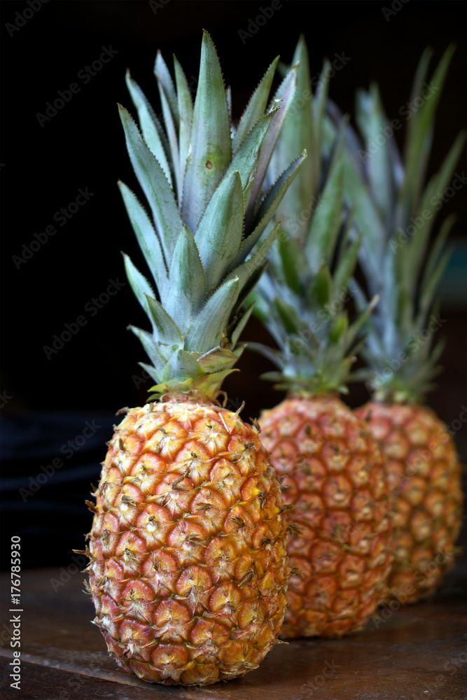 Three pineapples in a row on wooden table Three pineapples in a row on wooden table