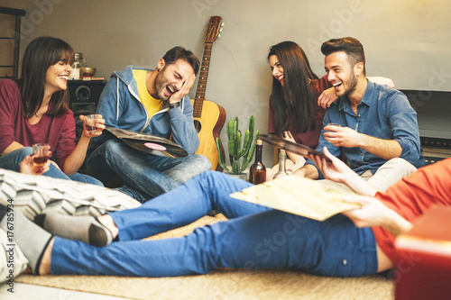 Wall Mural Happy young friends having fun at home listening vintage vinyl disc music in liv