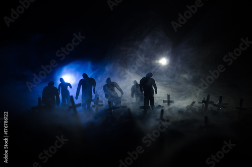 Silhouette of zombies walking over cemetery in night. Horror Halloween concept of group of zombies at night