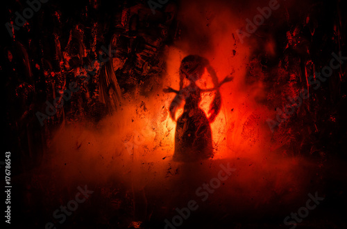 Horror silhouette of girl behind the matte glass blood stain. Blurry hand and body figure abstraction. Background with fire.