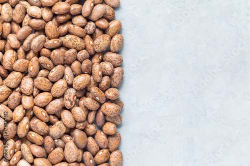 Uncooked dry pinto beans on gray concrete background, top view, copy space, horizontal