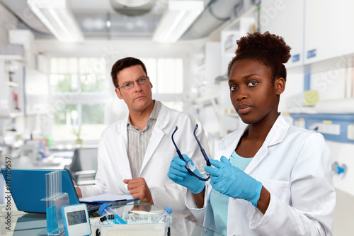 Scientists, Caucasian male and African female, work in laboratory