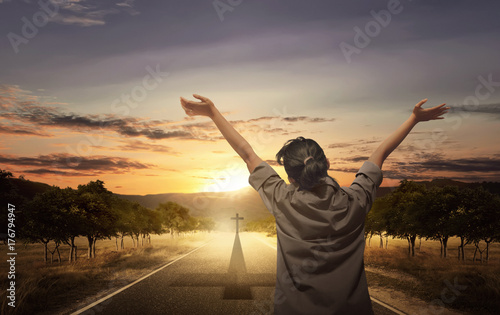 Back view of woman raising hand with open palm while praying