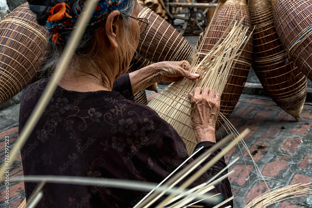 Closeup Old Vietnamese female craftsman hands making the traditional bamboo  fish trap or weave at the old traditional house in Thu sy trade village,  Hung Yen, Vietnam, traditional artist concept Stock Photo