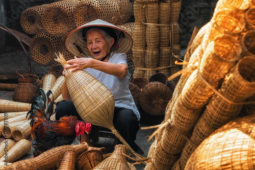 Obraz na płótnie Old Vietnamese female craftsman making the traditional bamboo fish trap or weave at the old traditional house in Thu sy trade village, Hung Yen, Vietnam, traditional artist concept w salonie