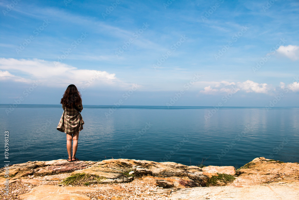 Backpacker girl stands on the viewpoint of the vast ocean.