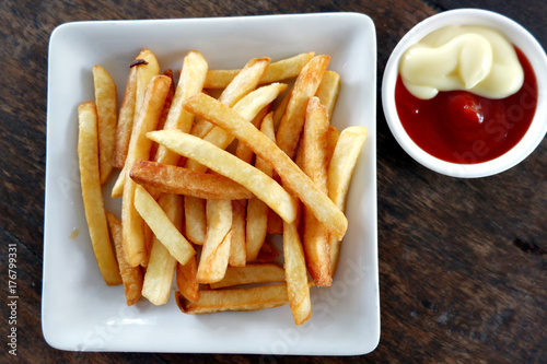 French fries and tomato sauce In the dish on a wooden table.