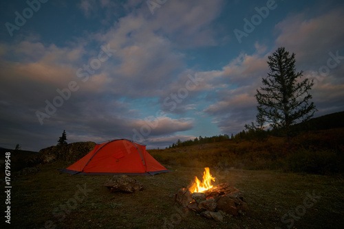 A tent and campfire under an evening sky