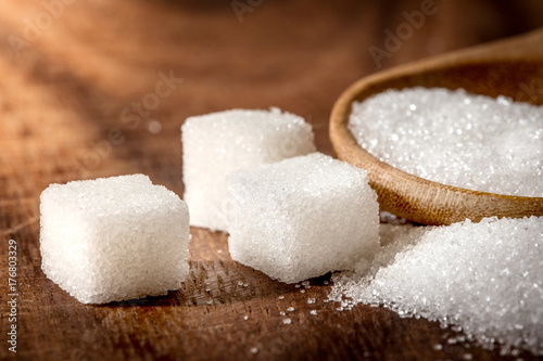Close up  sugar cubes and cane in wooden spoon on the table ,retro color tone
