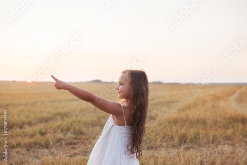 Little beautiful smiling girl on a gold wheat field walking at sunset. Happy five years old girl smiling and laughing in summer day at nature. Happyness freedom and carefree childhood concept