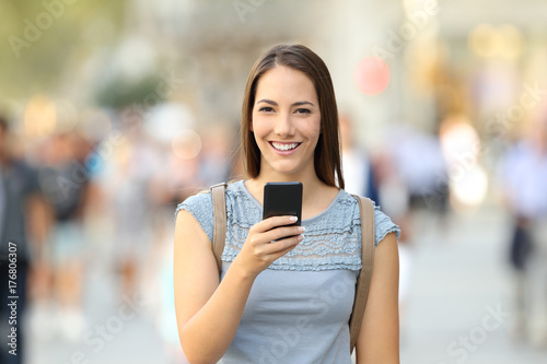 Happy woman holding a phone looking at camera