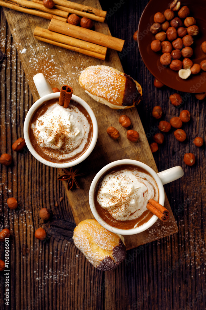 Hot chocolate with whipped cream sprinkled with aromatic cinnamon in cups on a wooden table, top view.  Delicious and warming drink.  