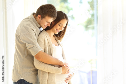 New parents looking at belly of pregnant mother