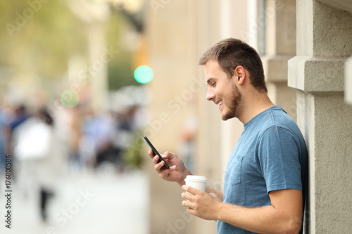 Side view of a man using a smart phone on the street