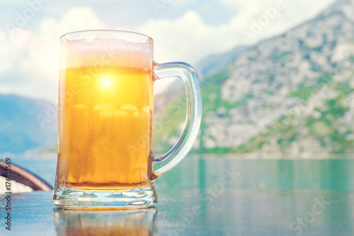 Mug of beer on the background of the sea and mountains in the sunlight