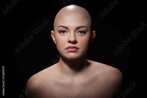 Fototapeta Portrait of a bald girl on a black background.