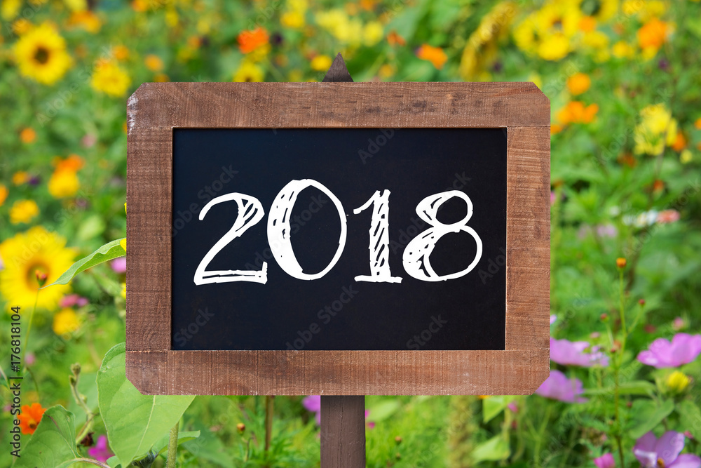 Φωτογραφία 2018 written on a wooden sign, Sunflowers and wild flowers in the background
