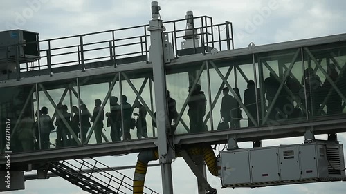 Passengers boarding on airplane through a jetway photo