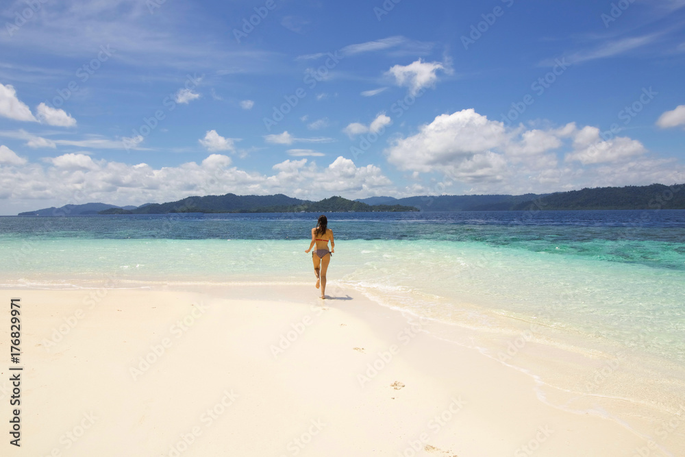 young woman running on a wild atoll towards the sea