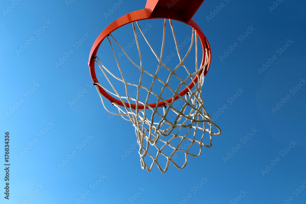 Orange basketball rim (hoop) and white net against blue sky seen from below