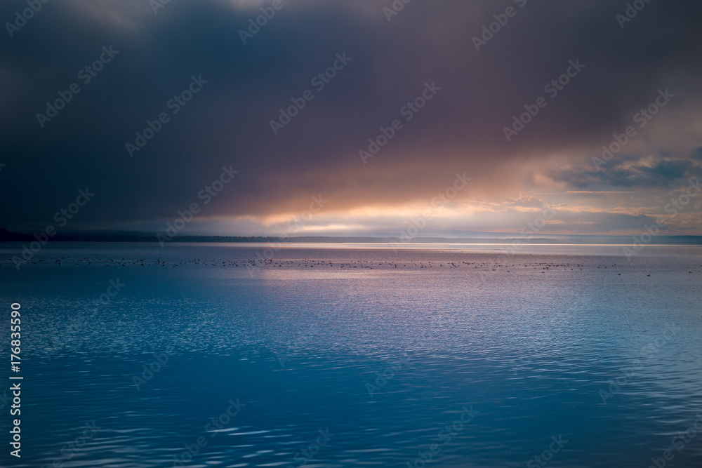 Fototapeta premium Beautiful sunrise. Dramatic clouds over mountain lake. Ducks on the water surface.