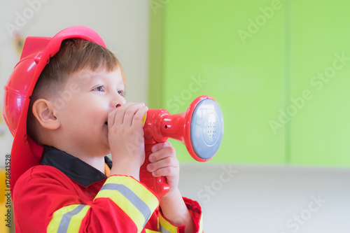 Caucasian boy kid dress up to fireman and use speaker at roll play classroom,Kindergarten preschool education concept