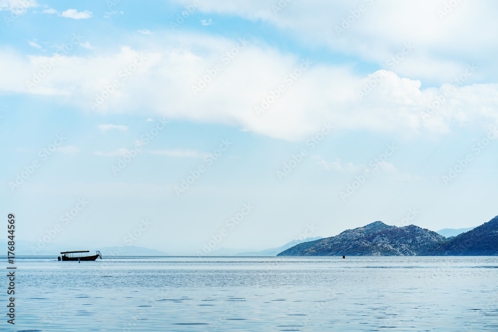 Amazing view on tranquil lake water and mountains landscape with boats on a horizon. Skadar lake, Montenegro Amazing view on tranquil lake water and mountains landscape with boats on a horizon. Skadar lake, Montenegro
