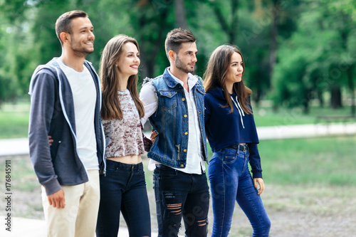 Four young smiling friends relax in park