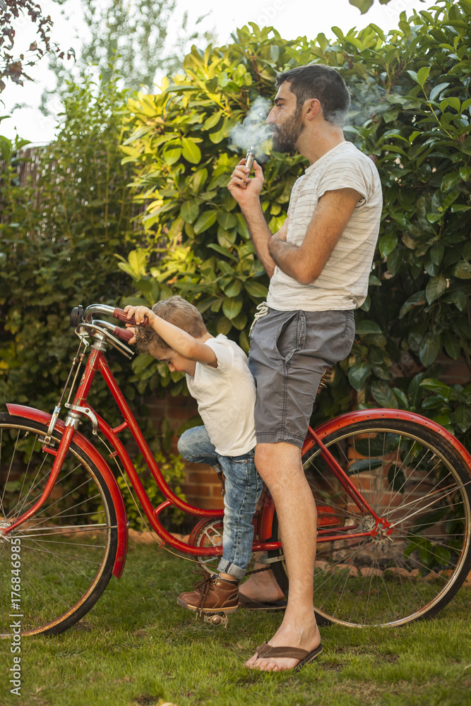 Portrait child dressed as a rocker driving a big red vintage bycicle with dad