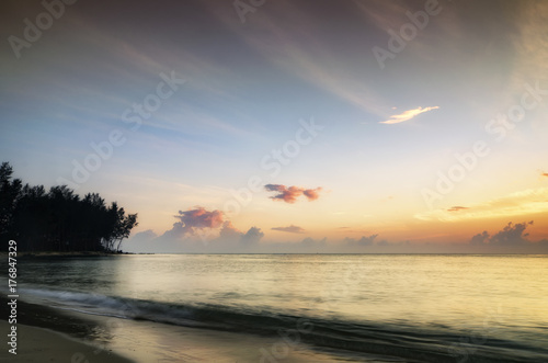 beauty in nature, silhouette image of beach scenery during sunrise. cloudy sky and soft wave htting  sandy beach © amirul syaidi