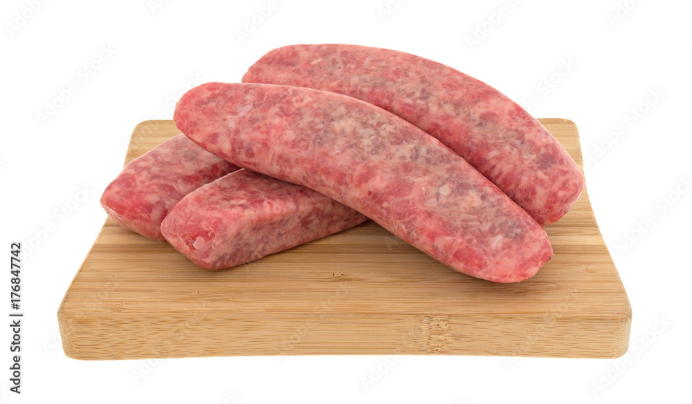 Several mild bratwurst sausages on a wood cutting board isolated on a white background. Several mild bratwurst sausages on a wood cutting board isolated on a white background.