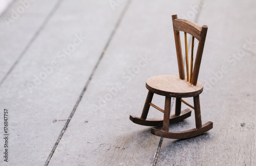 miniature chair on wooden floor expressing lonely feeling and missing someone concept