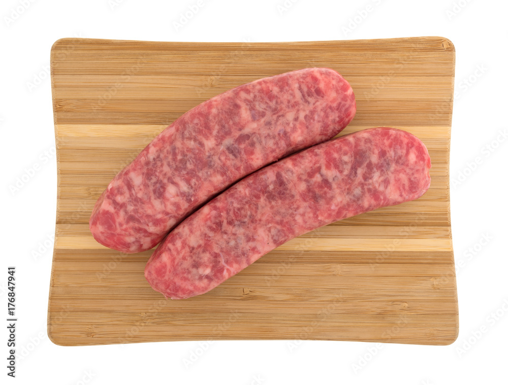 Top view of two mild bratwurst sausages on a wood cutting board isolated on a white background. Top view of two mild bratwurst sausages on a wood cutting board isolated on a white background.