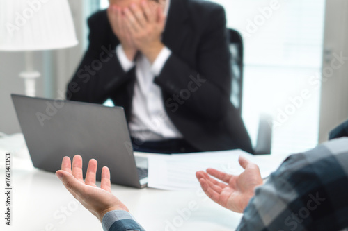 Failed job interview or business people having fight in office. Businessman covering and holding face with hands in meeting. Boss do not want to fire employee. Bad management or working environment