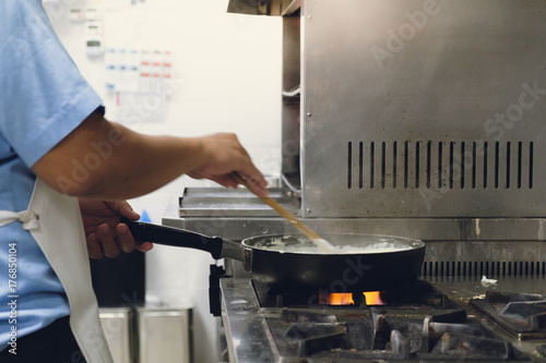 Cooking sauce with cheese in pan by chef hands on gas stove