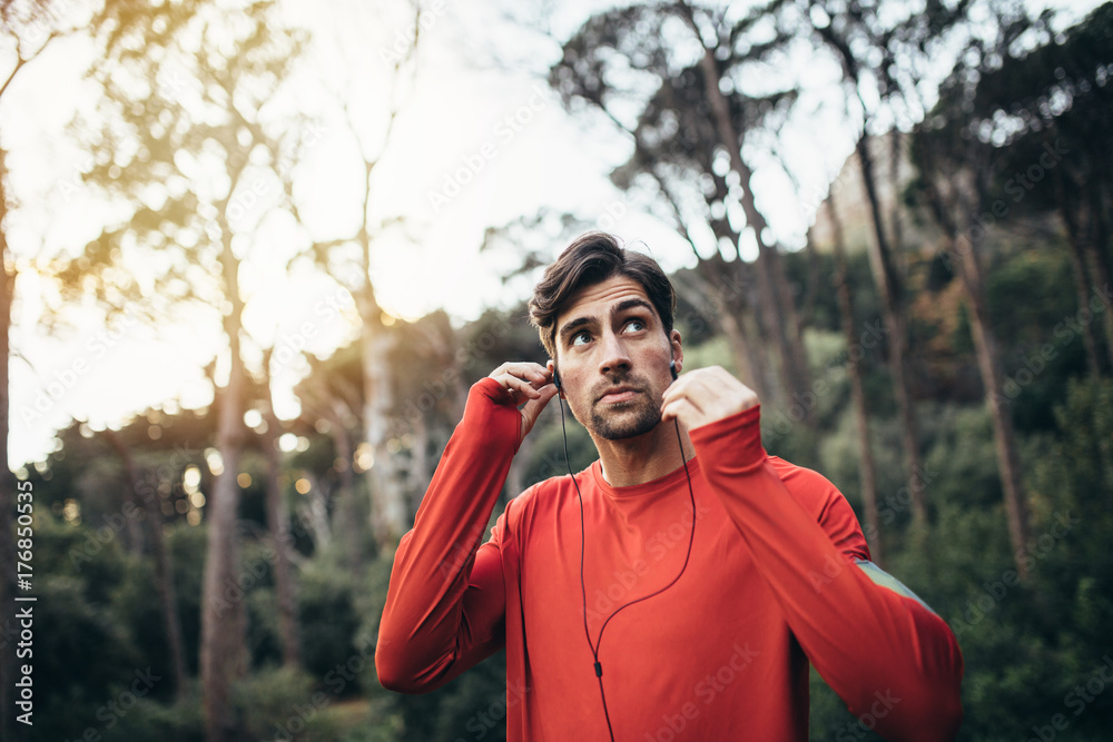 Runner wearing earphones during workout in a park Runner wearing earphones during workout in a park
