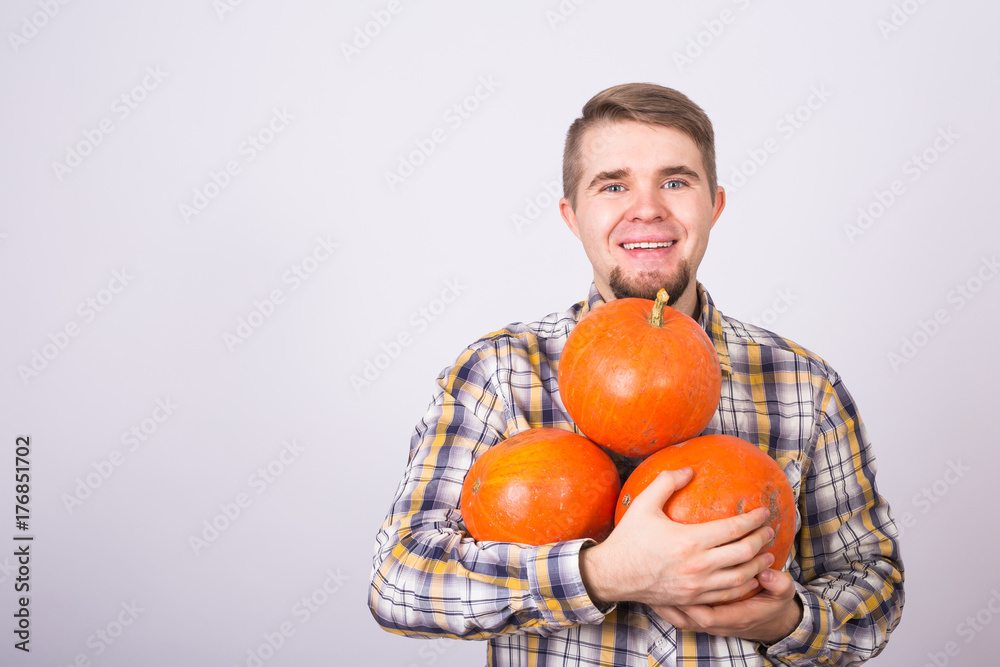 portrait of a young farmer holding a pumpkins on a light background studio portrait of a young farmer holding a pumpkins on a light background studio