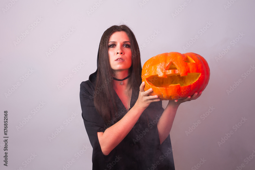 Halloween witch holding a orange pumpkin Jack o Lantern with smoke Halloween witch holding a orange pumpkin Jack o Lantern with smoke