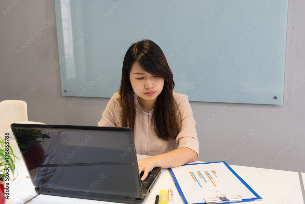 Young office lady inputting data in chart into laptop Young office lady inputting data in chart into laptop