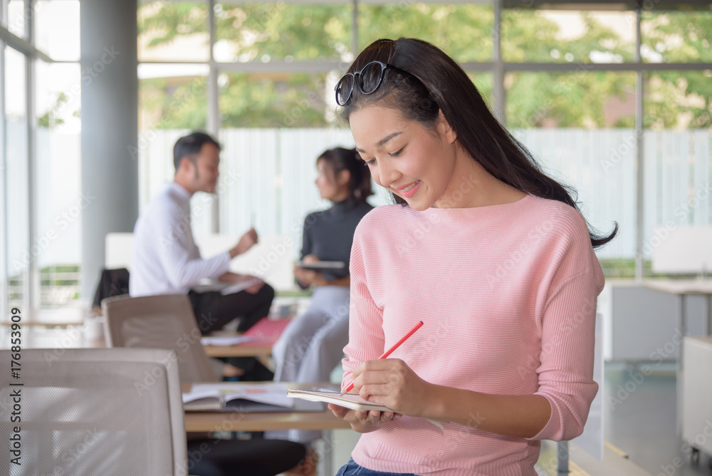 Asian businesswoman writes on a document in startup office Asian businesswoman writes on a document in startup office