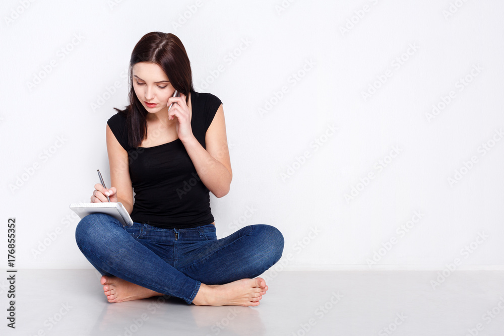 Woman talks on phone, sitting on home floor